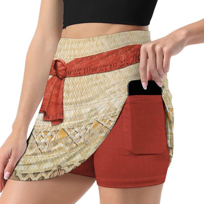 A woman wearing a skirt with a red belt and a patterned design. She is holding a cell phone in her pocket.